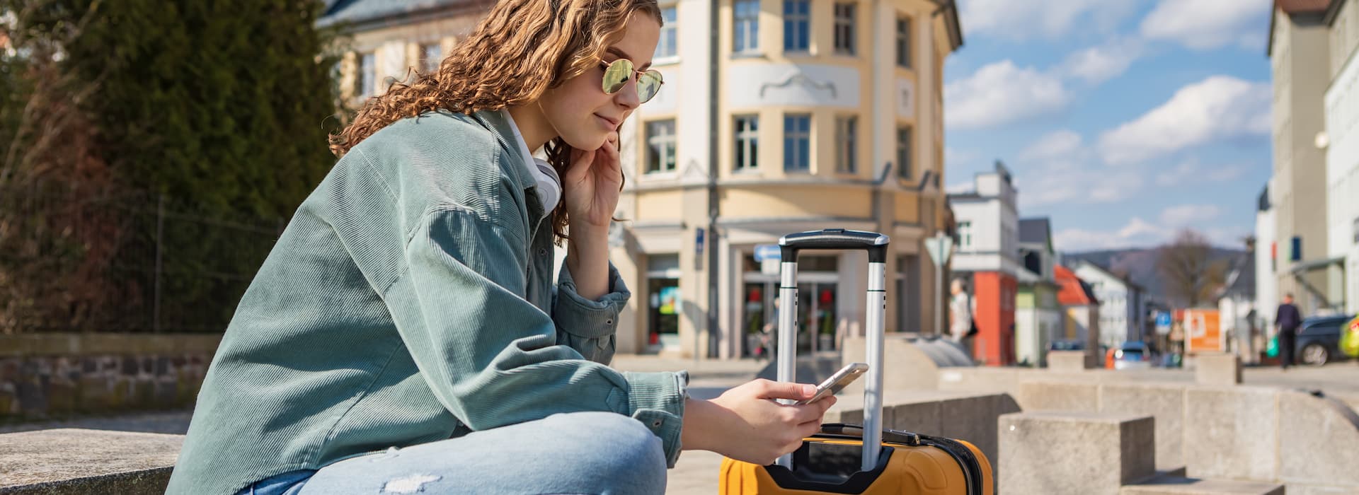 Traveller on cellphone sitting on a bench in German city